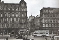 an old black and white photo of a city street with cars, buses and people