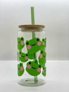 a glass jar filled with green and pink frog stickers next to a wooden lid