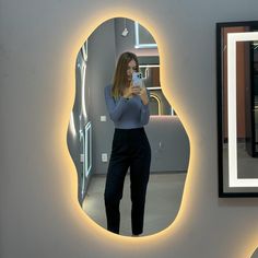 a woman taking a selfie in front of a mirror with her cell phone on the wall