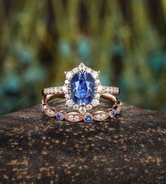 a blue and white diamond ring sitting on top of a rock with grass in the background