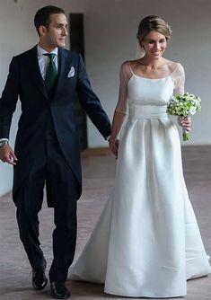 the bride and groom are walking down the hall together in their wedding attire, holding hands