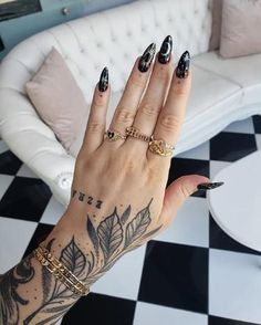 a woman's hand with black and white designs on it, holding onto a couch