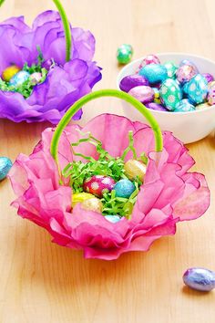 three baskets filled with candy and flowers on top of a wooden table next to easter eggs