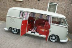 an old vw bus with its doors open and the interior door ajar, parked in front of a brick building