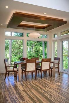 a dining room table and chairs in front of large windows with wood flooring on both sides