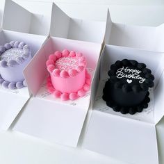 four birthday cakes in different boxes on a white table with the words happy birthday written on them