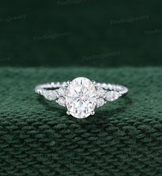 an oval cut diamond engagement ring on green velvet