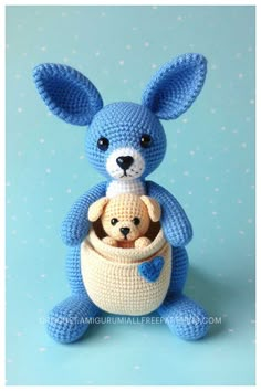 a crocheted blue bunny holding a teddy bear