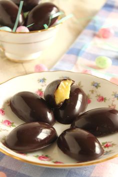 some chocolate covered eggs on a plate with a flowered table cloth and bowl in the background