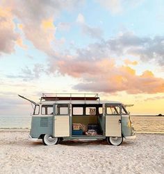 an old vw bus is parked on the beach with its doors open at sunset