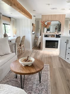 a living room filled with furniture and a fire place next to a kitchen in the background