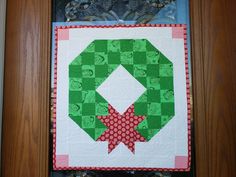 a close up of a green and red quilt on a door frame with an ornament