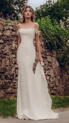 a woman in a white wedding dress standing on the side of a road with her arms around her waist