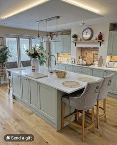 a large kitchen with an island in the middle and two stools at the end