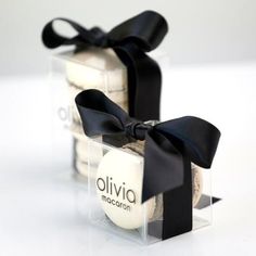 two clear boxes with black bows on the top and bottom are filled with white chocolates