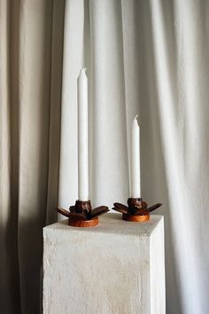 two candles sitting on top of a white block