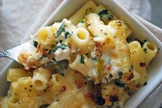 a white bowl filled with pasta covered in cheese and spinach sprinkles