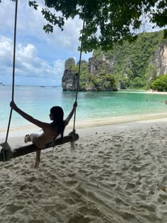 a woman sitting on a swing at the beach