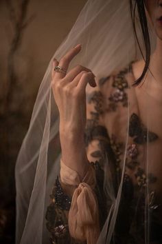 a woman wearing a veil and holding her hand up to the camera with both hands