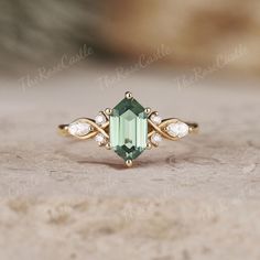 an emerald colored ring with three diamonds on the side and one stone in the middle