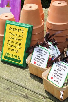 some potted plants are sitting on a picnic table with tags attached to the planters