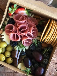 a box filled with assorted fruits and crackers on top of a wooden table