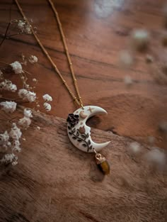 a necklace with an animal's skull and flowers on it sitting on a wooden surface