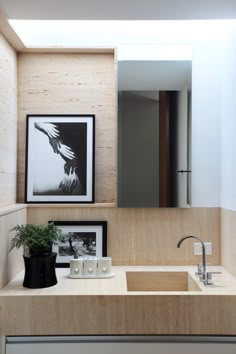 a bathroom sink sitting under a mirror next to a framed picture on the wall above it