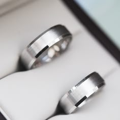 two wedding rings sitting on top of each other in a white box with black edges