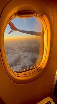 an airplane window looking out at the snow covered ground and land below it, as seen from inside