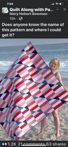 a woman standing on top of a beach holding a red, white and blue quilt