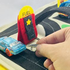 a person is playing with a toy car on the road that's made out of felt