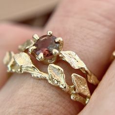 a close up of a person's hand holding a ring with leaves on it