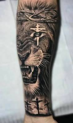 a man's arm with a lion and cross tattoo on it, in black and grey