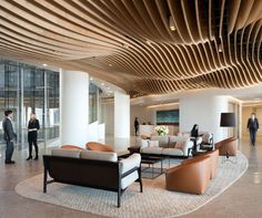 people are standing in an office lobby with couches, chairs and lamps on the walls