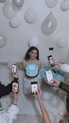 four people holding up cell phones in front of a cake