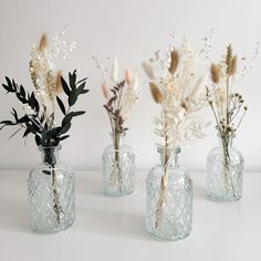 three glass vases with dried flowers in them