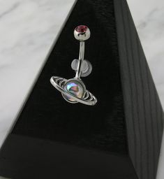 a pair of piercings with an opal in the center on a black stand