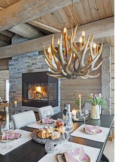 a dining room table with place settings and candles on the tables in front of an open fire place