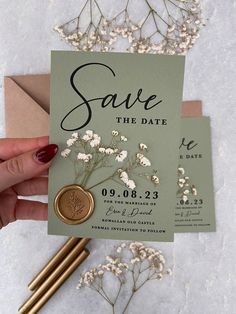 save the date card with wax stamp and flowers on it next to some envelopes