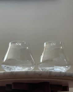 two empty glasses sitting on top of a counter next to each other, with the word sm written on them