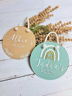 two personalized door hangers on a white wooden background with dried flowers and leaves