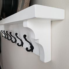 a white shelf with black hooks on it