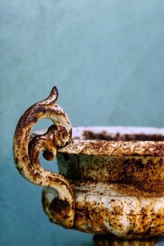 a rusted cup sitting on top of a table next to a blue wall and floor