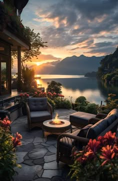 a patio with chairs and fire pit in front of a lake at sunset or sunrise