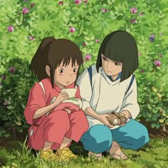 two people sitting on the ground in front of some bushes and flowers, one holding a baseball bat