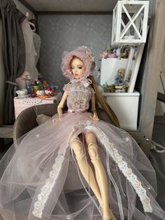 a doll sitting on top of a chair wearing a dress and headpiece with veil