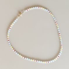 a white beaded necklace with multicolored beads and a gold plated clasp