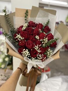 a bouquet of red roses is being held by someone's hand in a store