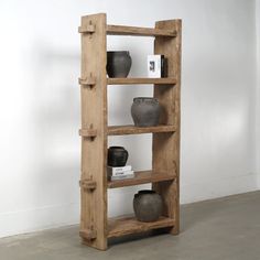 a wooden shelf with vases on it in front of a white wall and floor